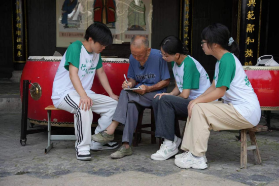 许传成向“三下乡”实践队员介绍磡头老鼓